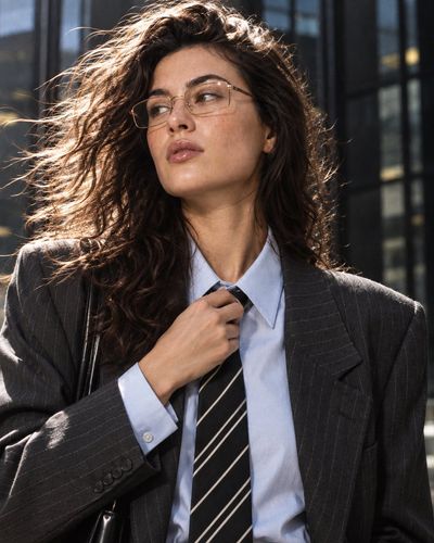 Windblown Woman in Pinstripe Blazer Gazing Past Camera