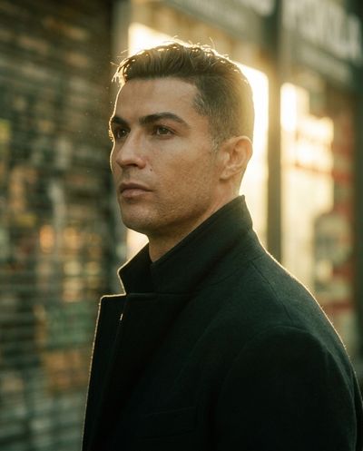 Football star in a black coat stands alone at golden hour