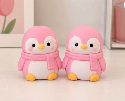 Two adorable pink penguin figurines on pastel tabletop