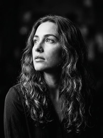 Woman with wavy hair gazes upward in dramatic chiaroscuro portrait