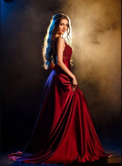 A crimson gown catches the golden backlight in a smoky room.
