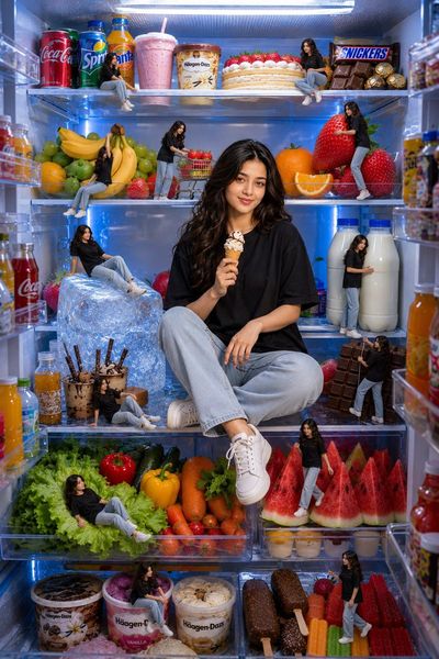 Young man in refrigerator enjoys ice cream among tiny clones