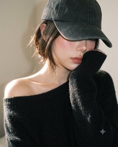 A soft dreamy portrait hides eyes under a dark baseball cap