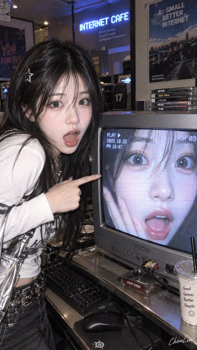 She points at a CRT screen showing her own shocked face