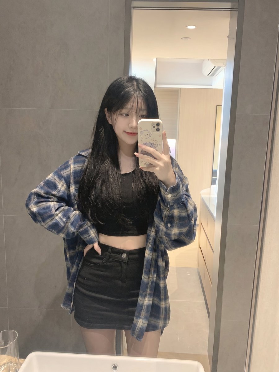Young girl in plaid flannel takes a playful mirror selfie
