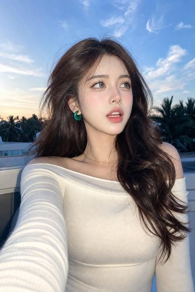 Woman in white top looks up at blue hour sky from rooftop