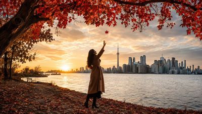 Golden hour woman reaches for the last red leaf in Toronto