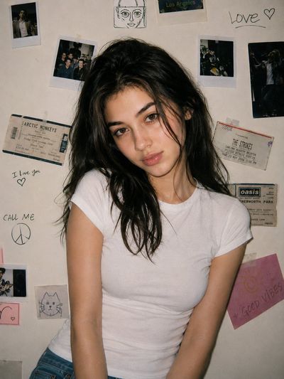 Young woman in white tee smirks under soft flash