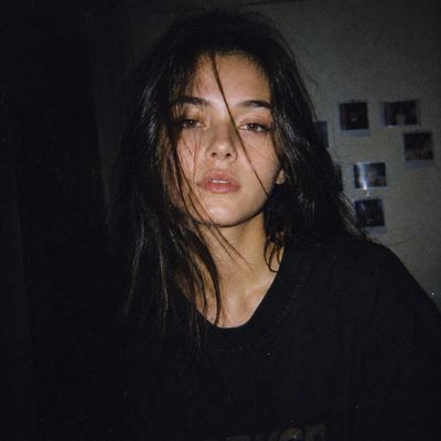 Japanese woman with pale skin stares calmly in dim flash snapshot