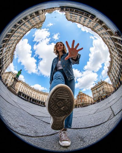 A sneaker dominates the foreground as a hand reaches toward the lens