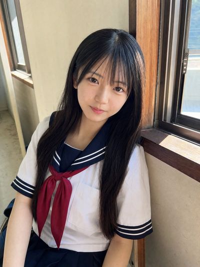 Japanese schoolgirl leans by window in soft daylight