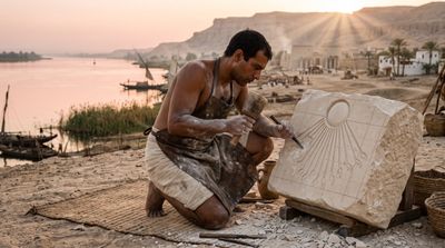 Egyptian sculptor carves Aten sun disk beside the glowing Nile