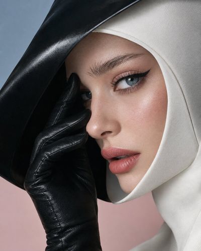 Futuristic beauty with black hood and leather glove frames face