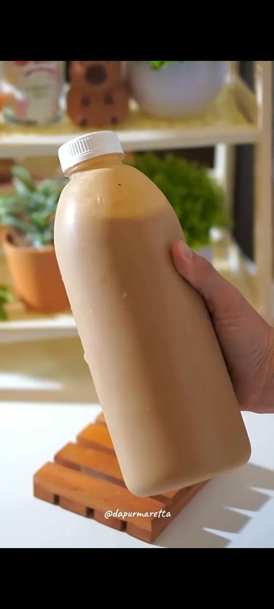 Hand Holds Chilled Caramel Coffee in Beige Bottle With Condensation