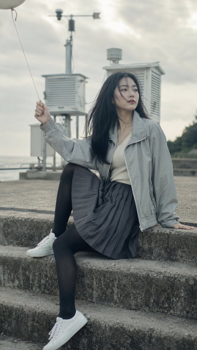 A K-pop idol sits on foggy steps holding a white balloon