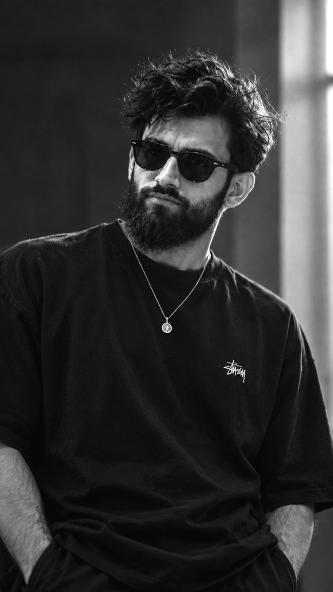 Monochrome portrait captures brooding man with thick beard indoors