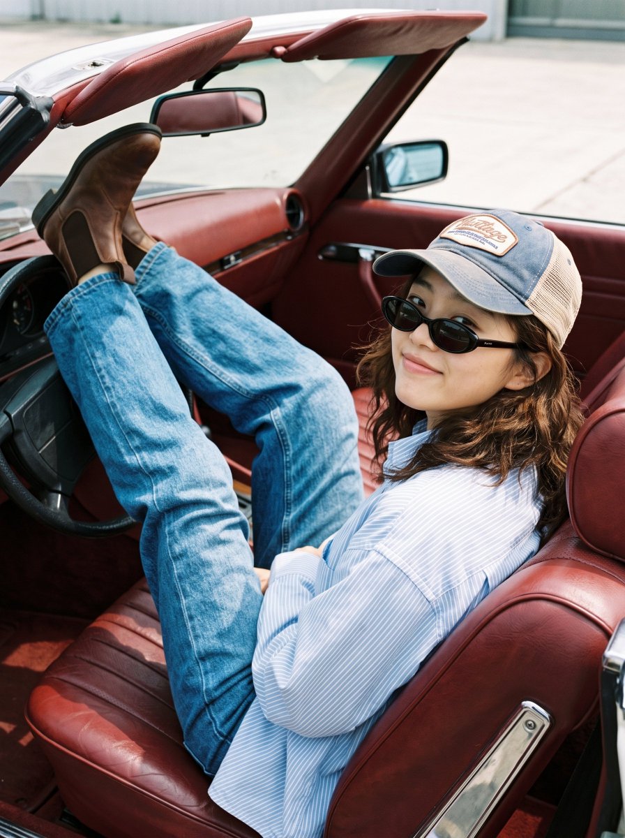 Woman in striped shirt lounging in vintage convertible under bright sun