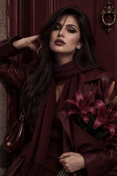 Woman in burgundy leather poses against matching door