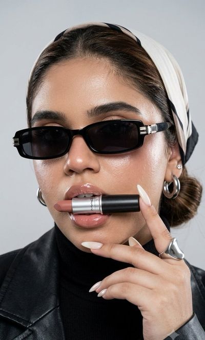 A model holds a lipstick between her teeth in a studio