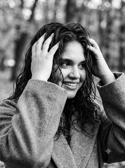 Monochrome close-up captures girl playing with hair in wind