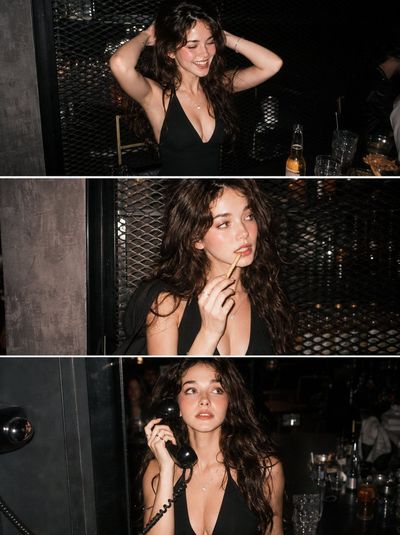 Young woman laughs with hands behind head at trendy bar