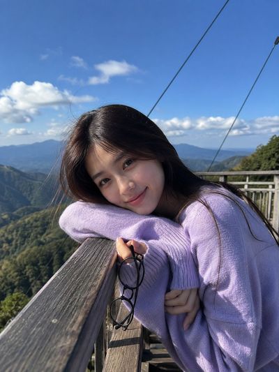 Young woman in lavender sweater poses at mountain viewpoint