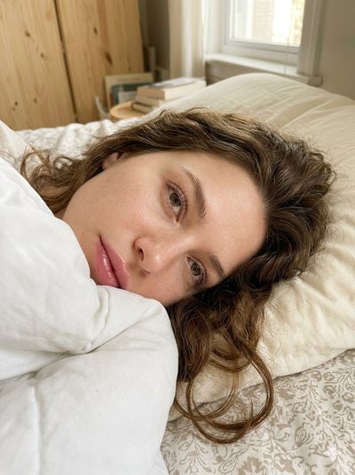 Young woman with porcelain skin gazes dreamily in warm morning sunlight