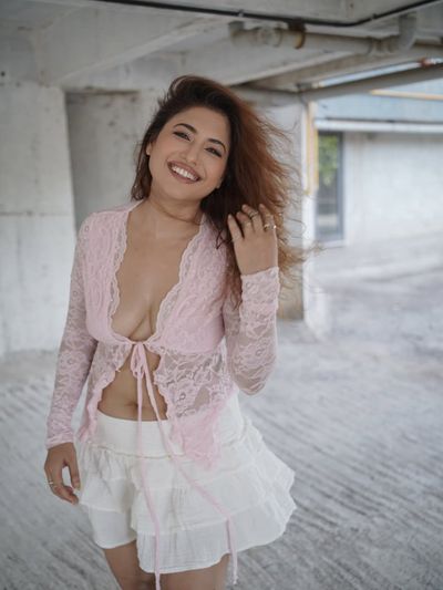 Radiant woman in pink lace smiles amid concrete pillars