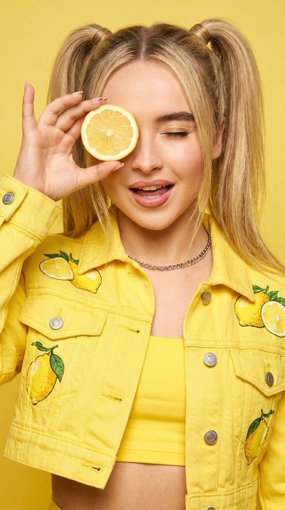 A playful girl holds a lemon slice in a yellow studio