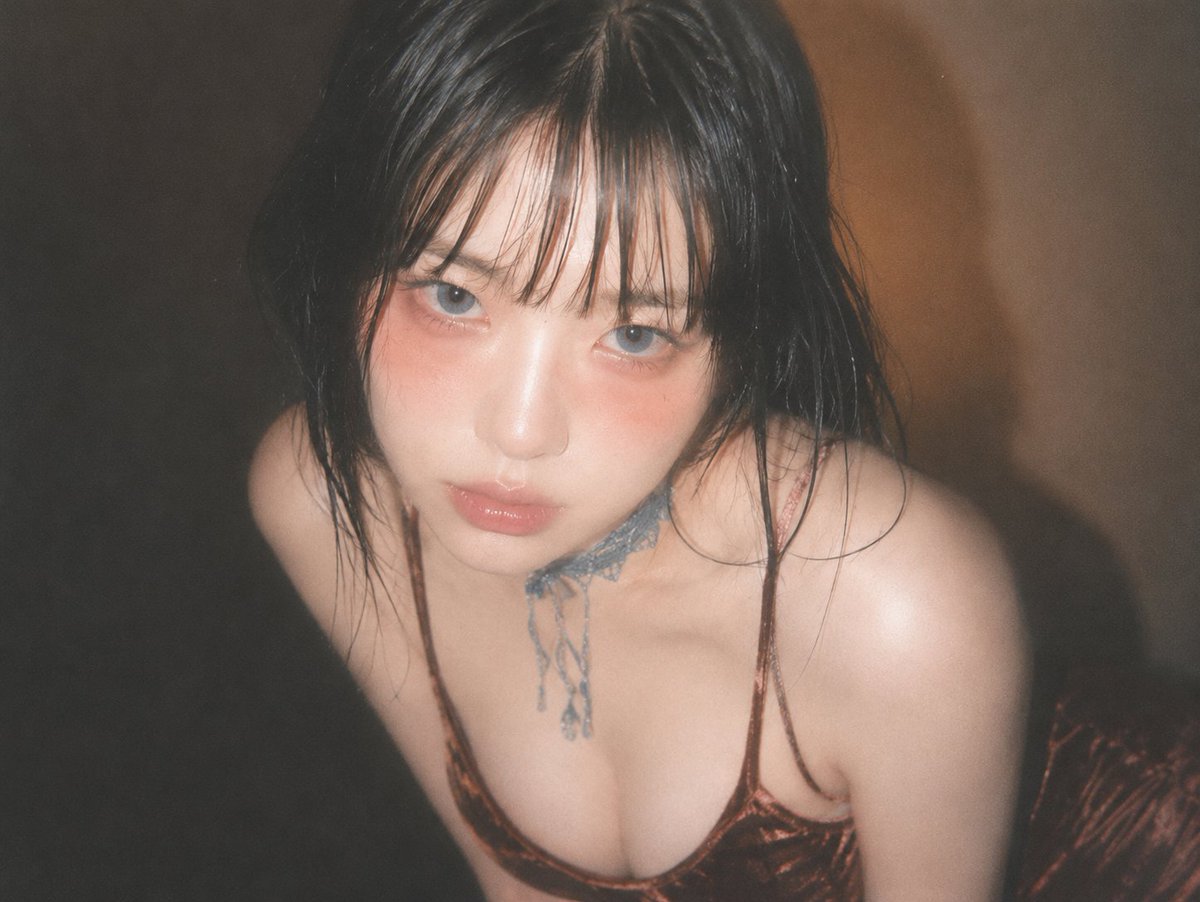 A young woman in velvet top gazes upward with soft flash