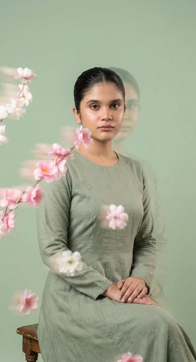 A young woman with serene expression drifts among sage flowers