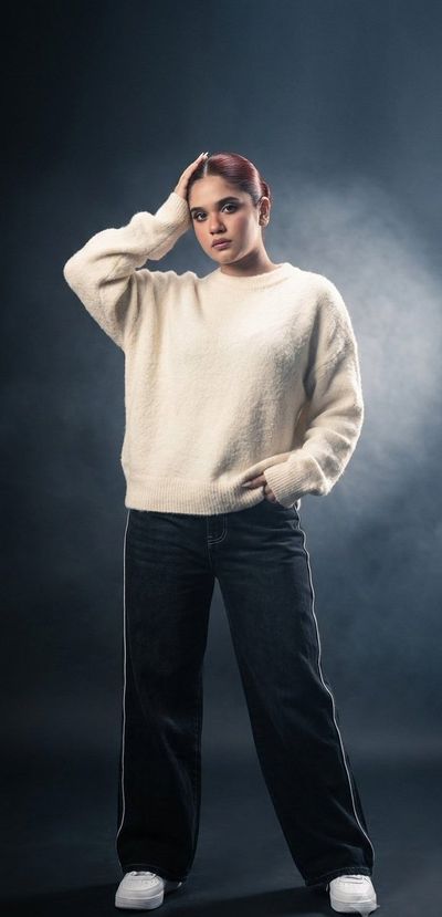 Oversized cream sweater meets relaxed high-fashion stance in studio