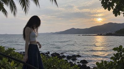 Young woman stands on seaside walkway under dull tropical dusk light