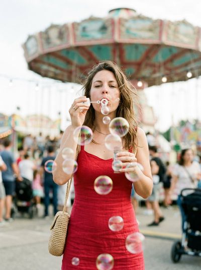 Woman blows soap bubbles at a worn summer carnival