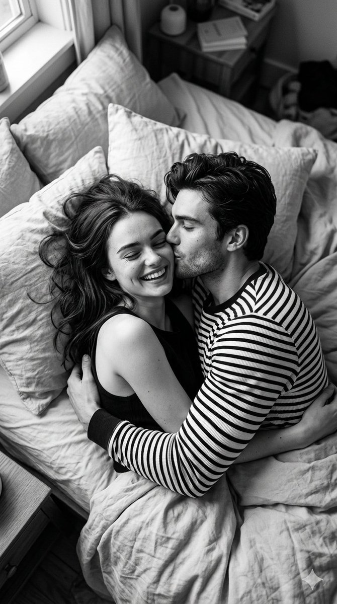 A young couple shares a tender morning kiss on rumpled bedsheets