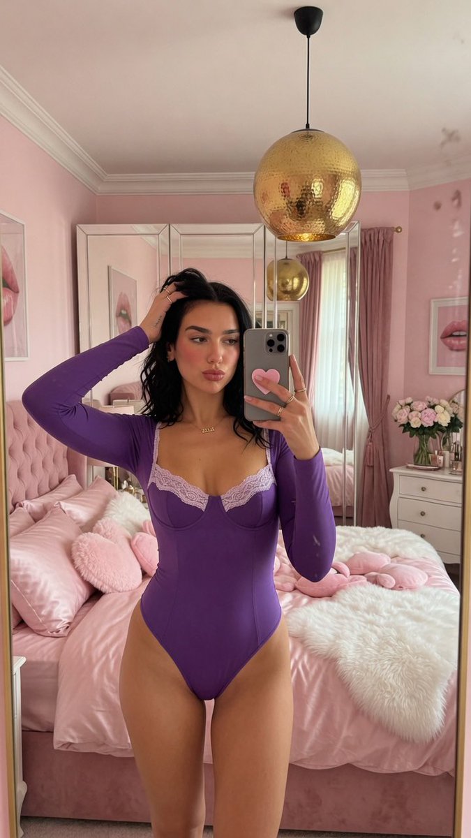 Woman in black lace bodysuit takes mirror selfie in pink bedroom