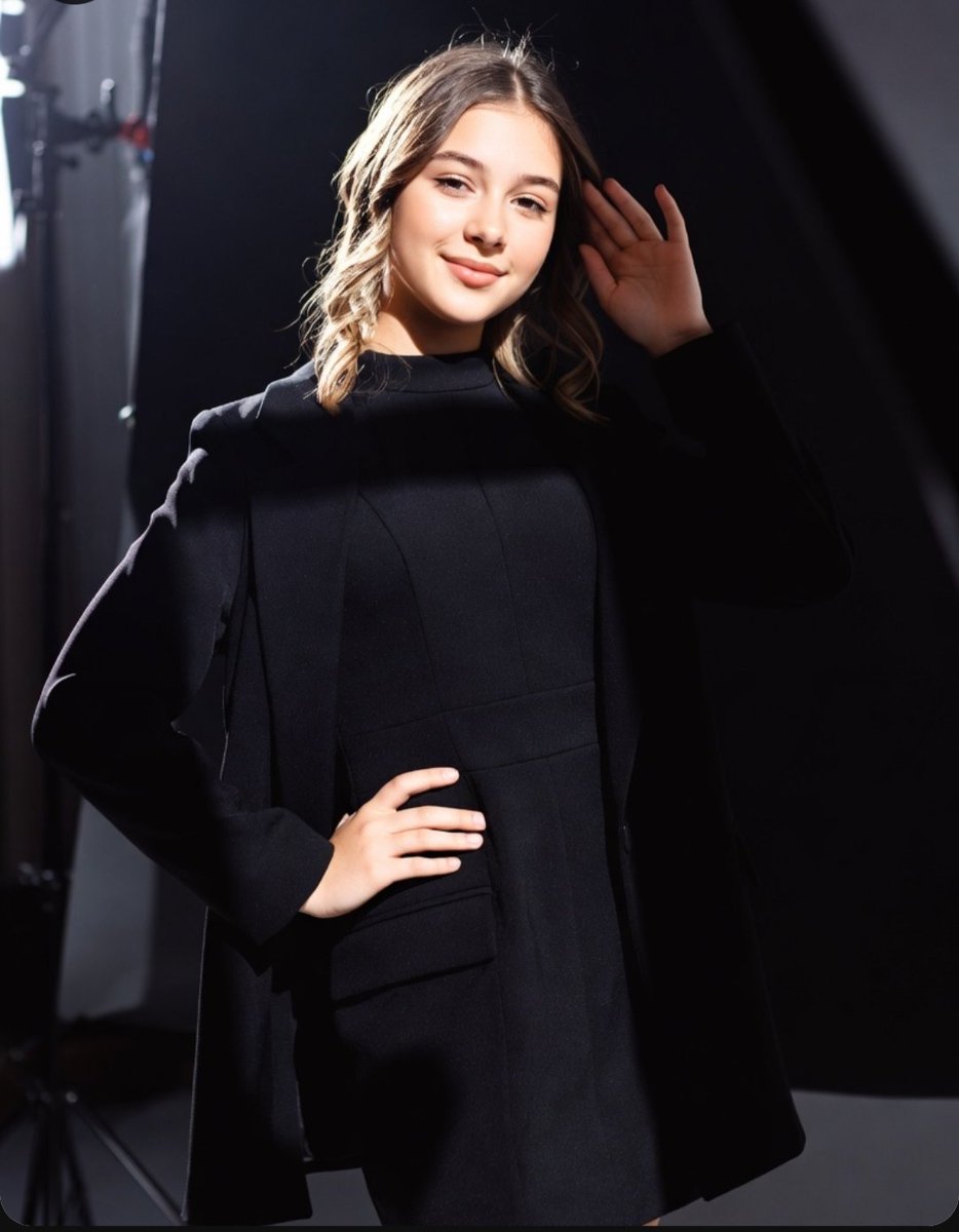 Confident model poses in dramatic studio light with chic blazer.