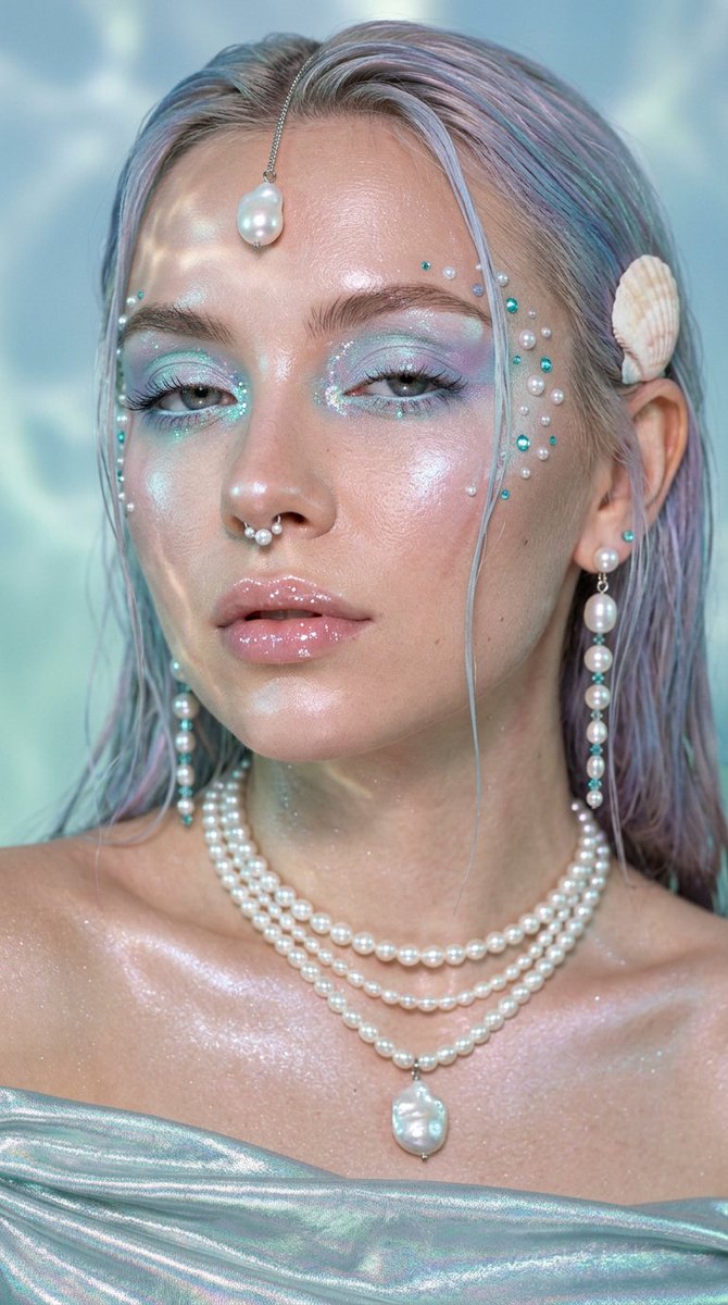Pearl-adorned mermaid gazes upward in cool aquatic light