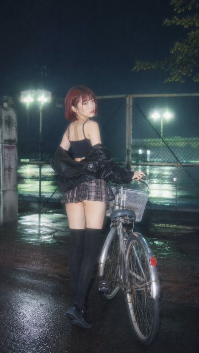 A Korean beauty with red hair glances back beside a vintage bike