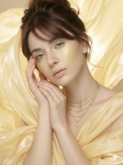 Ethereal woman with iridescent silk in soft pink studio light