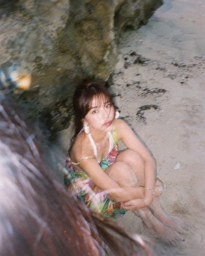 A woman crouches on the beach under a limestone cliff at sunset