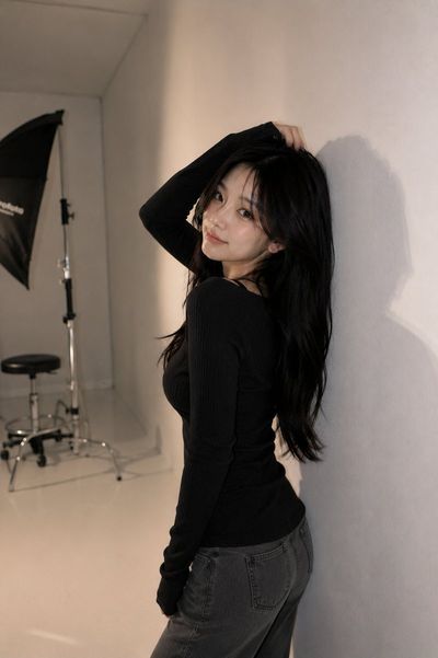 Korean model poses elegantly against gray studio wall with soft lighting