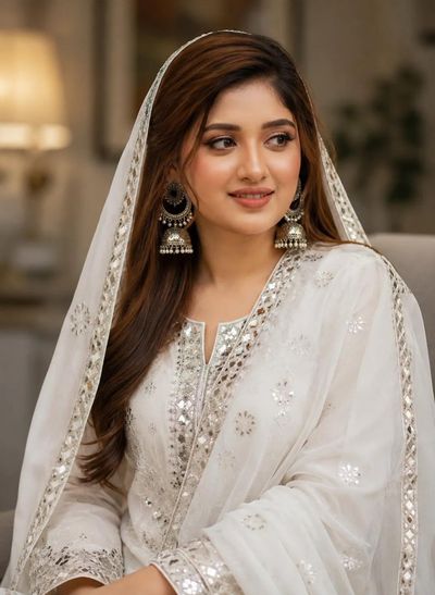 South Asian woman in embroidered white outfit looks away in portrait