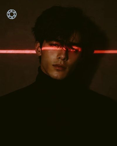 A woman's calm face illuminated by a red laser across both eyes.