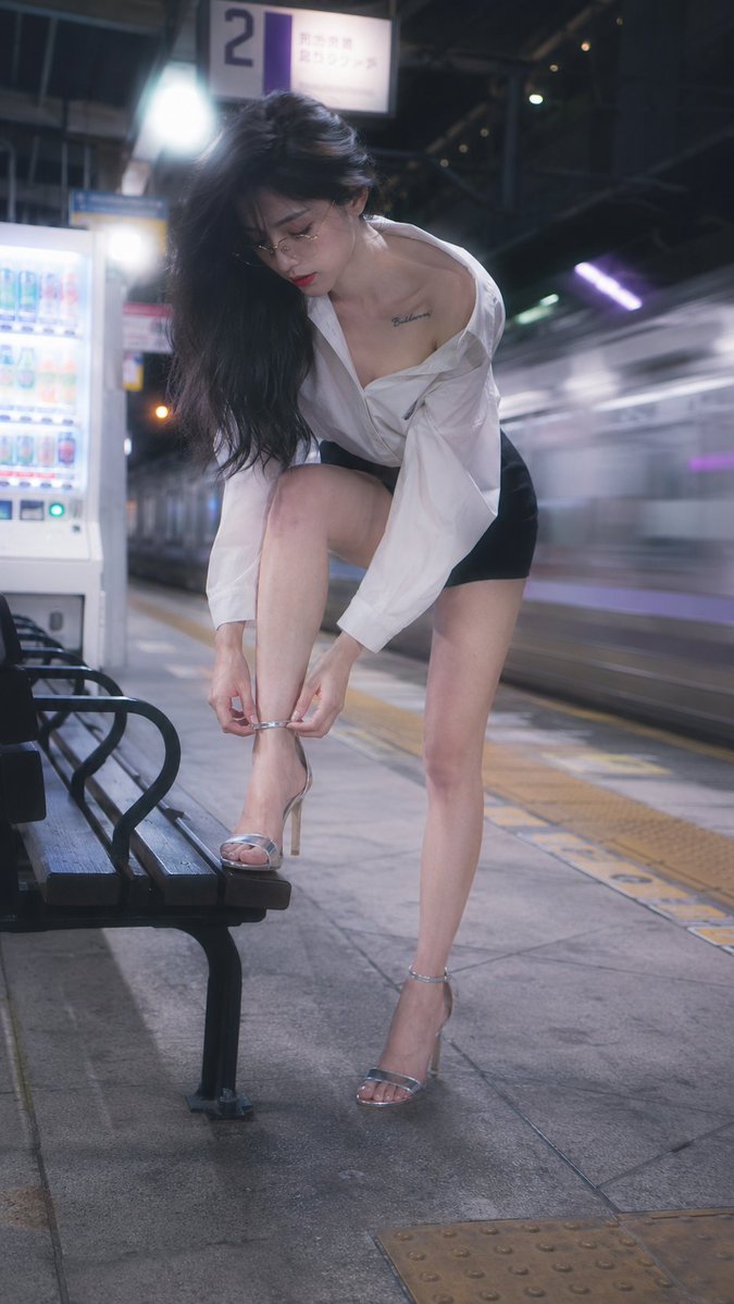Idol bends to fasten her heel on a quiet platform
