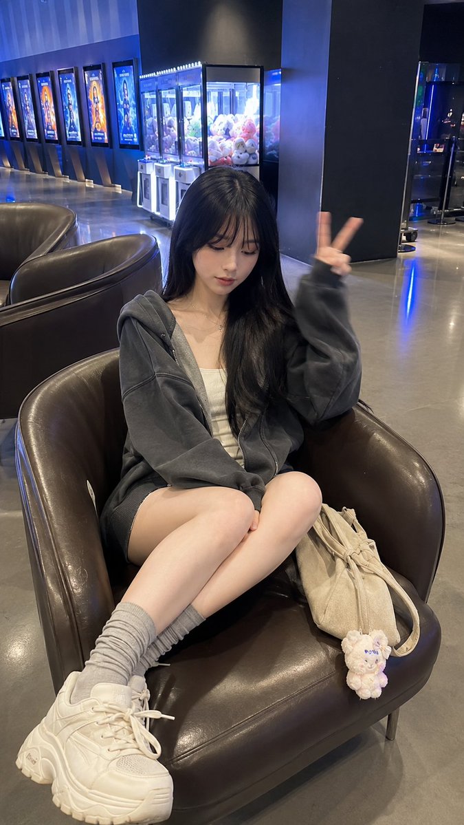 Young woman rests in cinema lobby with peace sign gesture
