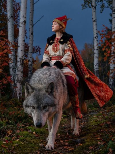 Giant grey wolf leads red-caped rider on moonlit mossy trail