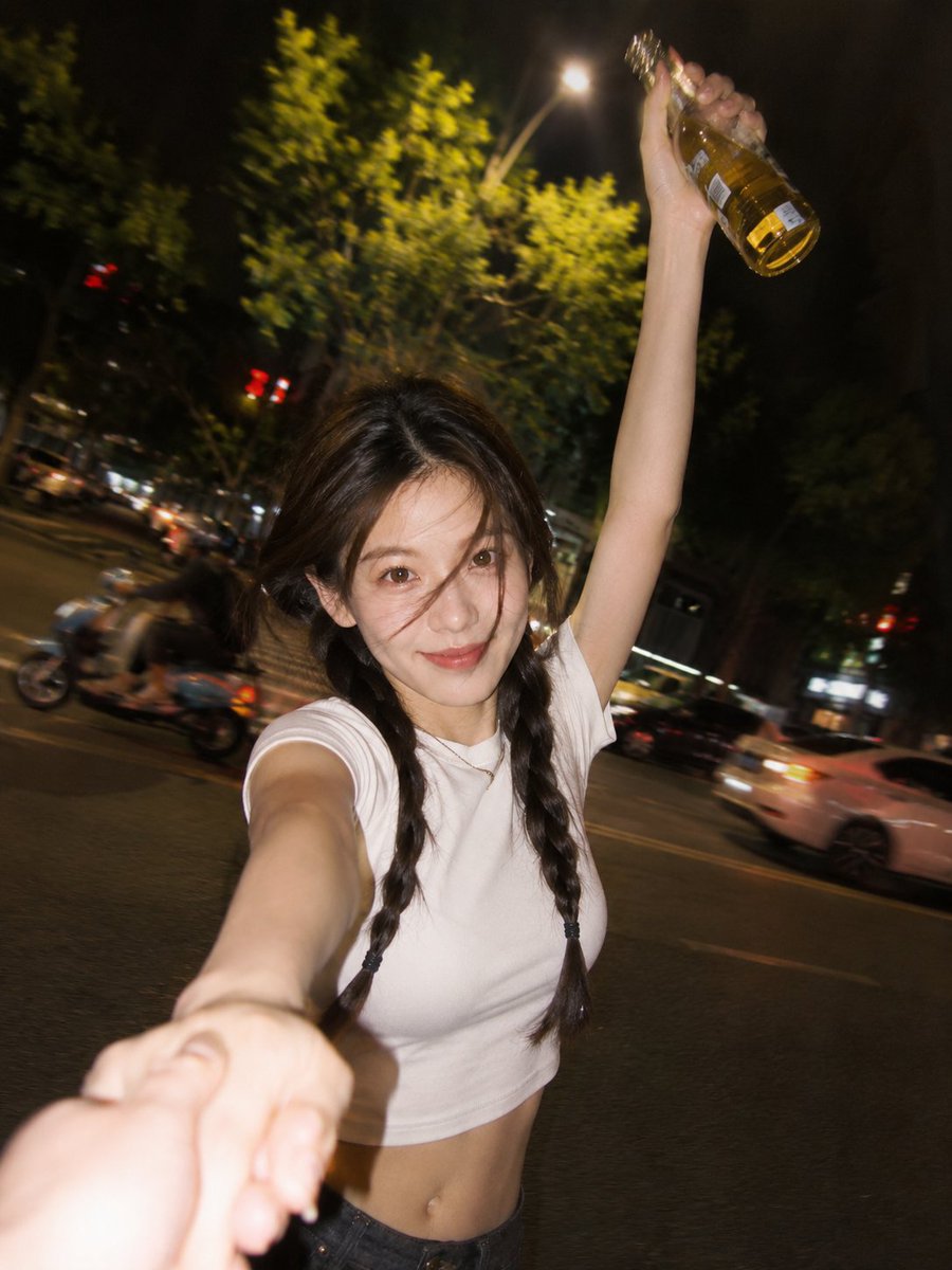 A smiling woman holds a golden drink in a night street