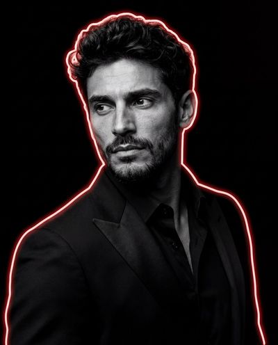 A man in black suit with red neon rim light looks away