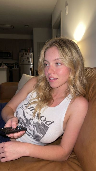 A woman reclines on a couch watching late night TV